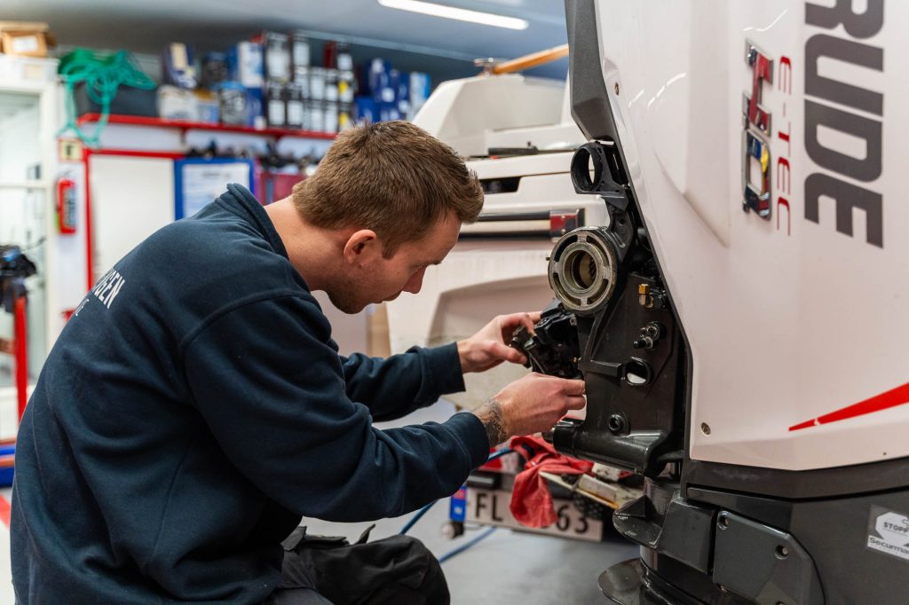 Bilde av en båtmekaniker som skrur på en båtmotor fra Evindrude